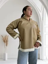 Buzo color beige de ecocuero con capucha, cierre frontal parcial y puños y ruedo con borde de piel sintética blanca.