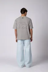 Remera de algodón gris con efecto acid wash, corte regular, mangas cortas y cuello redondo. Cuenta con un pequeño bordado tono sobre tono en el pecho y una etiqueta lateral distintiva de la marca en el ruedo.