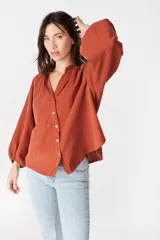 Camisa de corte holgado y diseño asimétrico, con cuello mao, cierre frontal de botones y mangas largas abullonadas con puños elásticos.