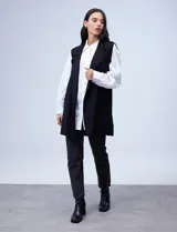 Chaleco largo de punto marca Absolutely Famous, color negro, con cuello de solapa y bolsillos delanteros.