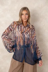 Camisa oversize de gasa con estampado de cadenas en tonos bordó y rosado. Presenta cuello clásico, cierre frontal con botones y mangas largas con puños abotonados.