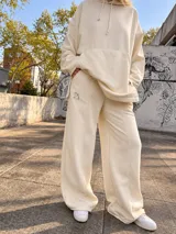 Pantalón jogger ancho color beige, con bolsillos laterales y pequeño bordado de un arco y flecha en la parte superior.