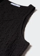 Musculosa negra con textura arrugada y cuello redondo.