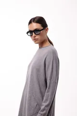 Sweater de silueta amplia y largo medio, con cuello redondo, mangas largas y detalle de botones decorativos en los laterales. Presenta un diseño de tejido de punto con caída relajada.