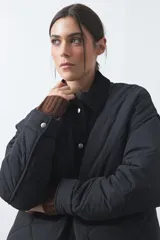 Campera tipo barn capitoneada de color marrón, con silueta corta y relajada. Presenta cuello de pana, cierre frontal con broches metálicos y bolsillos laterales funcionales.