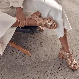 Sandalias de cuero color dorado con tiras cruzadas estilo gladiadora, taco cuadrado y talón cerrado.
