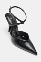 Zapato de tacón alto tipo destalonado, con acabado en punta y escote redondo. Presenta una tira fina ajustable con hebilla metálica en el tobillo y tacón fino.
