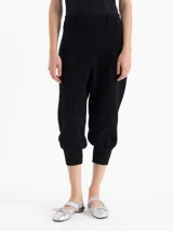 Pantalon negro de corte tipo babucha, con cintura estructurada, presillas para cinturón, bolsillos traseros y ruedos ajustados con puños tejidos.