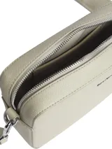 Cartera bandolera Calvin Klein modelo Must, color beige con textura granulada y correa ancha ajustable con logo de la marca.