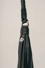 Cartera tipo hobo de gamuza color marrón, con correa trenzada de cuero negro y detalles laterales en cuero negro.