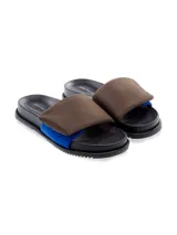 Sandalia tipo slide de cuero, color negro, con tira ancha acolchada en la parte superior y una tira inferior de color fucsia/magenta brillante. La suela es negra con borde dentado. Se observa texto en la plantilla que parece ser 'yuko imanishi+'.