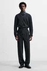 Bolso bandolera negro de cuero con bolsillo plano frontal y correa larga del mismo material.