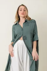 Camisa larga de manga corta, calce holgado, color verde con estampado de motivos en forma de medallones o cuadrados con diseño ornamental.