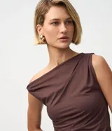 Blusa de microfibra color amarillo claro, sin mangas, con escote de hombro único, detalle torcido en el hombro y fruncidos en todo el diseño. Presenta un corte ajustado y bajo asimétrico.