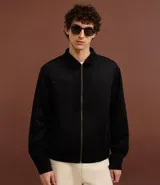 Campera masculina de estilo casual con cuello inglés, cierre frontal por cremallera, bolsillos laterales y ajuste elástico en el bajo. Presenta detalles de recortes en la parte superior delantera.