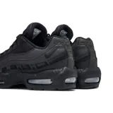 Zapatilla deportiva Nike Air Max 95, completamente negra (triple black), con capas superpuestas de materiales sintéticos y malla, y unidades Air Max visibles en el antepié y el talón.