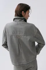 Campera de denim 100% algodón a rayas verticales en tonos grisáceos y azules. Cuenta con cuello camisero, cierre frontal con botones plateados y cuatro bolsillos frontales con botón.