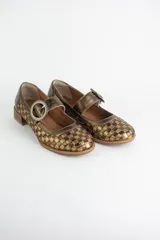 Zapato estilo Mary Jane confeccionado en cuero trenzado con acabado metalizado en tonos bronce y dorado. Presenta una tira con hebilla circular metálica sobre el empeine y un taco cuadrado bajo de madera.