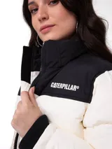 Campera puffer Caterpillar de diseño bicolor, con cuerpo en color crema y canesú superior en negro. Presenta cierre frontal completo, cuello alto, puños internos de punto acanalado y logo de la marca estampado en el pecho.