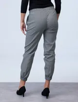 Pantalón jogger con estampado cuadrillé en blanco y negro, con pretina ancha elastizada con frunces, bolsillos laterales y ruedo con elástico fruncido.