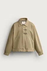 Cazadora relaxed fit de algodón color beige con efecto lavado, cuello solapa, bolsillos de plastrón en la cadera, cierre frontal de cremallera oculta y alamares metálicos.