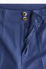 Pantalón de tiro alto confeccionado en lona de algodón, con diseño de pierna recta, raya marcada en el frente y la espalda, cierre con botones metálicos y bolsillos de parche en la parte posterior.