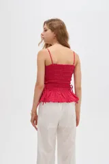 Top de algodón con diseño estampado de cuadros vichy en tonos celeste y blanco, corte al cuerpo con escote recto y tirantes finos. Presenta cuerpo fruncido tipo smock con cordones ajustables en los laterales que forman un pequeño volado en el ruedo.