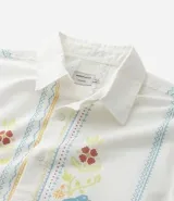 Camisa blanca de lino y algodón, de corte comfort, cuello inglés y abotonado frontal. Presenta manga corta y un bordado floral multicolor con motivos de aves y flores.