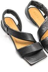 Sandalias chatas negras de cuero vacuno con punta cuadrada y tiras anchas.