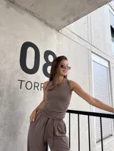 Conjunto de dos piezas compuesto por una musculosa de cuello redondo y un pantalón de corte holgado. Ambas prendas están confeccionadas en tejido morley elastizado de color marrón chocolate.