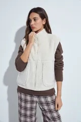 Chaleco de corderito color crema con cierre frontal, cuello alto y bolsillos amplios. Diseño de calce relajado y textura suave.