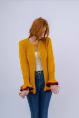 Saco de lana merino color mostaza, tejido a punto con detalle de volados en ruedo y puños. Tiene dos cierres frontales hechos en crochet a mano.