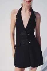 Mono negro de cuello halter con solapas, espalda descubierta y cierre frontal de botones con alamares.
