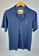 Camisa tejida azul marino de manga corta con cuello tipo polo y cierre frontal con botones. Presenta un pequeño logo bordado en el pecho.