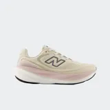 Championes de running New Balance modelo 1080 v15, con parte superior de malla transpirable en color beige. Presenta entresuela con tecnología de amortiguación en tonos blanco y rosado, y logo lateral en color gris.
