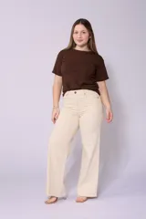 Jean de corte wide leg en color beige, con tiro alto y cierre frontal con botón y cremallera. Presenta un diseño de cinco bolsillos y costuras reforzadas.