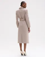 Abrigo largo color beige con corte recto y cintura anudada. Presenta motivos florales bordados a mano en tonos neutros y dorados en los bolsillos, mangas y bajo.