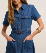 Vestido midi de jeans azul con cuello inglés, manga corta, abotonado delantero, bolsillos utilitarios y cinturón con hebilla redonda.