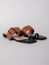 Sandalia baja negra de cuero sintético, con tira ancha sobre el empeine con hebilla metálica dorada y tira para el dedo.