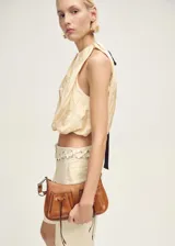Blusa color crema con cuello halter y lazo de ajuste en la espalda.
