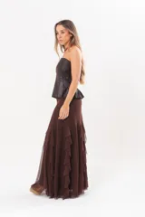Pollera larga color chocolate confeccionada en microtul, totalmente forrada, con diseño fluido y volados en cascada que aportan movimiento.