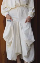 Pollera midi de lino con diseño inspirado en el corte babucha, caracterizada por su volumen, caída fluida y grandes bolsillos laterales tipo cargo. Presenta cintura elástica y un estilo relajado.