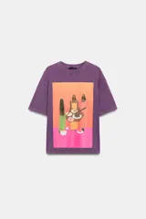Remera oversize de algodón con efecto lavado en color violeta. Presenta cuello redondo, manga corta y una estampa frontal colorida con una ilustración artística de Manuja Waldia.