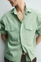 Camisa de corte relajado confeccionada en tejido fluido con mezcla de lyocell. Presenta diseño de rayas verticales, cuello solapa, manga larga con puños abotonados, bolsillos de plastrón con solapa en el pecho y cierre frontal con botones a presión.