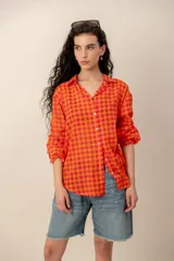 Camisa de manga larga con estampado tropical, fondo a rayas celestes y blancas, cuello camisero y cierre frontal de botones.