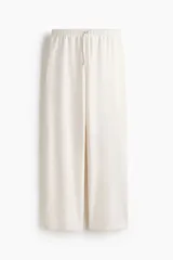 Pantalón tipo jogger de corte holgado y piernas amplias, confeccionado en felpa con interior cepillado. Presenta cintura elástica con cordón de ajuste y bolsillos laterales discretos.