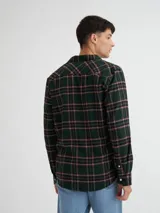 Camisa de manga larga a cuadros azules, confeccionada en viyela 100% algodón, con bolsillo en el pecho y botones de pasta. Presenta una etiqueta de cuero sintético en el ruedo y otra en la cartera.