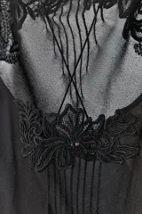 Vestido midi semitransparente de viscosa, con escote redondo y detalles de nervios marcados. Presenta tirantes finos dobles que se cruzan en la espalda y aplicaciones de bordados florales a tono en la parte superior.