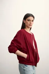 Chaqueta tipo bomber color negro, con cierre frontal metálico, cuello redondo y puños elásticos.