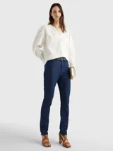 Blusa blanca de algodón orgánico con cuello en V, mangas largas abullonadas con puños abotonados y detalles de encaje vertical.